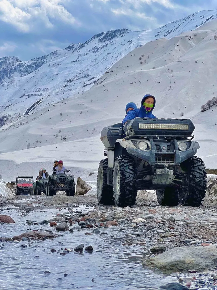 ATV riders crossing a mountain stream near Gudauri